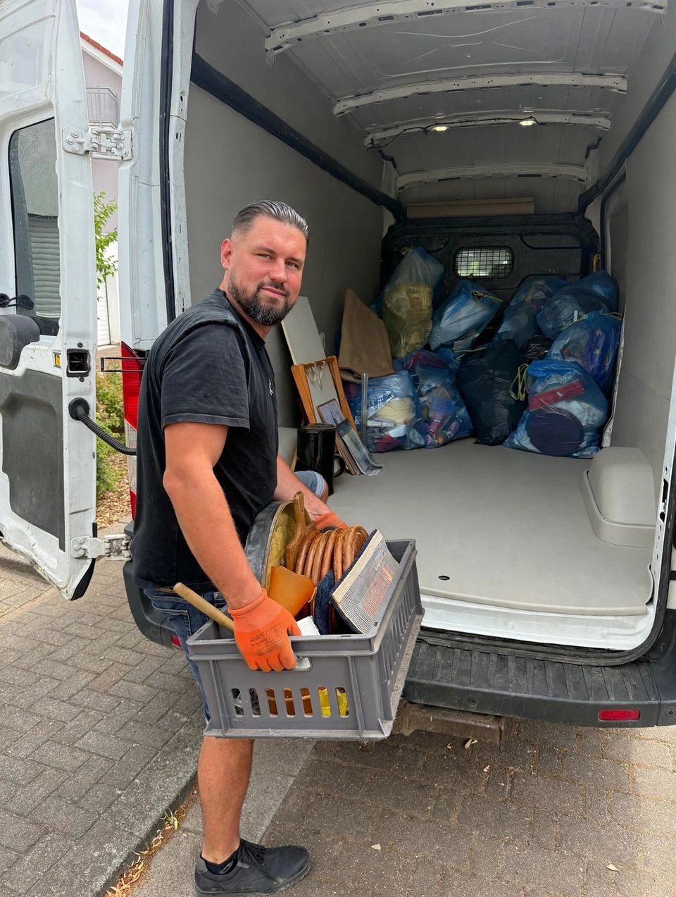 Sergej Scheiermann mit einer Kiste voller Hausrat vor seinem beladenen Transporter